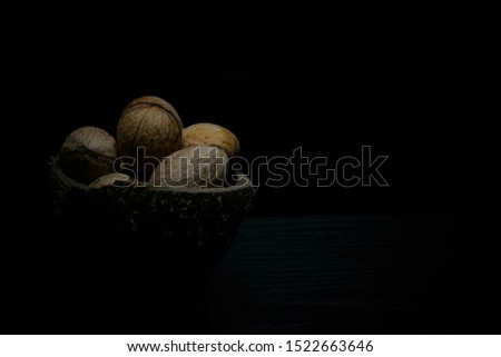 bowl with walnuts at the right side of the photo on black background
