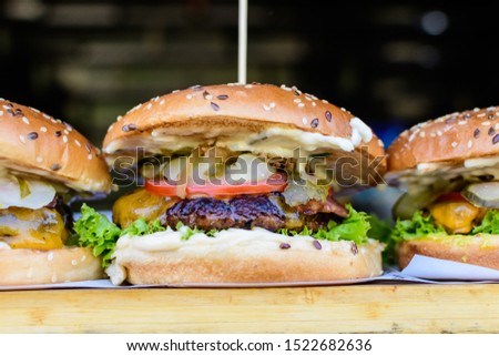Close up of a tasty hamburger sandwich, with grilled spiced meat with tomato, cucumber and mayonnaise, displayed for sale at an weekend street food market