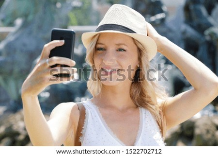 happy young woman taking selfie on city street