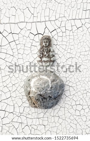 Buddha and Enso Circle Stone on cracked white background. 