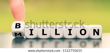 Hand turns a dice and changes the word "Million" to Billion". Royalty-Free Stock Photo #1522750655