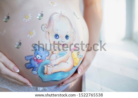 Lovely drawing on the stomach of a pregnant woman in the form of a cheerful baby
