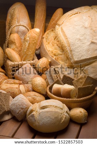 artisan breads of various types and shapes, wooden base, black background