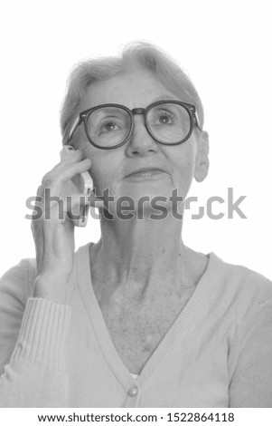 Face of senior nerd woman talking on mobile phone while thinking