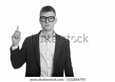 Studio shot of young businessman pointing finger up