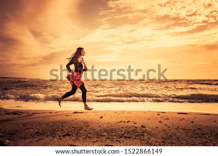 Woman doing beach run on the beach at sunset