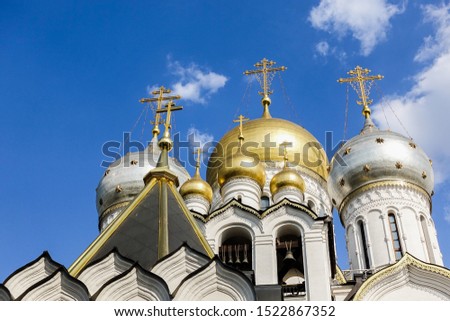 Golden domes with crosses of an orthodox temple on the background of bright blue sky. Snow-white facade. Christian faith. Royalty-Free Stock Photo #1522867352