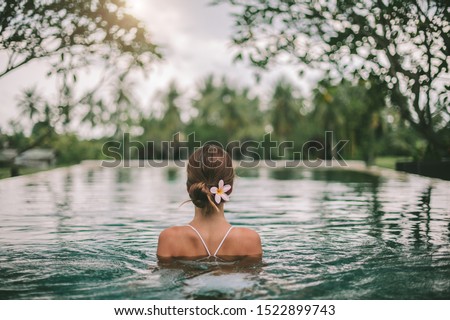 Young girl swimming in infinity pool with in private villa resort. Travelling to Ubud, Bali. Royalty-Free Stock Photo #1522899743