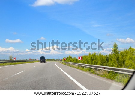 Track, road with signs from a car window. Blue sky and european road through glass trap