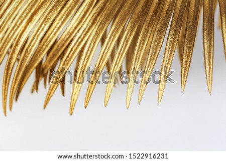 Golden colored leaf of palm close up. Painted metallic plants. Creative decoration background with nature pattern and natural texture.