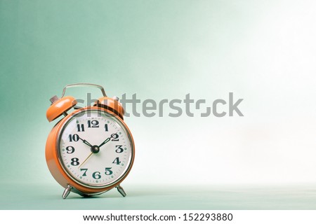 Retro alarm clock on table on mint green background Royalty-Free Stock Photo #152293880