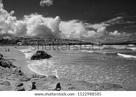 The Cornish beach at Polzeath on the North Cornwall coast, surfers and bathers enjoying the surf, sea and very dramatic white clouds in Summer time, Cornwall, UK