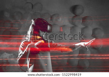 girl uses virtual reality helmet, concept of modern technology, effect of double exposure. Young woman playing VR games, fire special effects and computer graphics on the background of a gray image