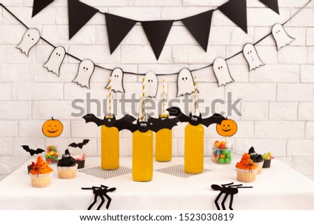 Halloween holidays. Children party with healthy drinks and tasty cupcakes on table