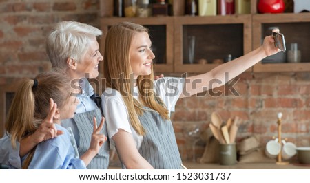 Mother, daughter and grandmother taking selfie at kitchen, side view, panorama with empty space