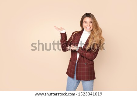 Studio shot of attractive friendly smiling happy caucasian woman wearing fashionable clothes , pointing sideway direction, smiling, presenting choices. Girl with long wavy hair and freckles