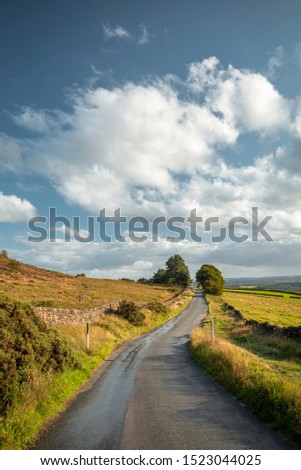 Empty asphalt countryside road across at warm summer evevning in Peak District National Park, UK