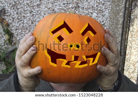 large pumpkin held in hands as a headwith a face on it