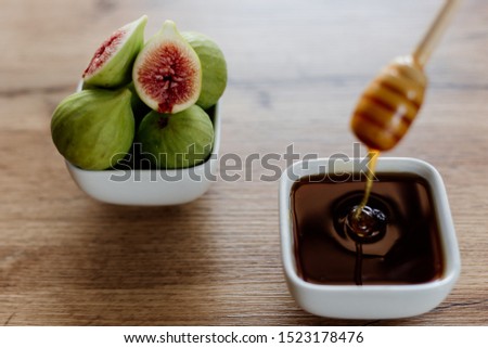 Figs and honey in a white bowl on wooden background