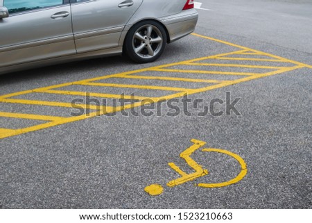 Silver car parking near handicapped parking sign area at asphalt parking lot, special car parking area for handicapped people only, transportation convenience for disabled people concept
