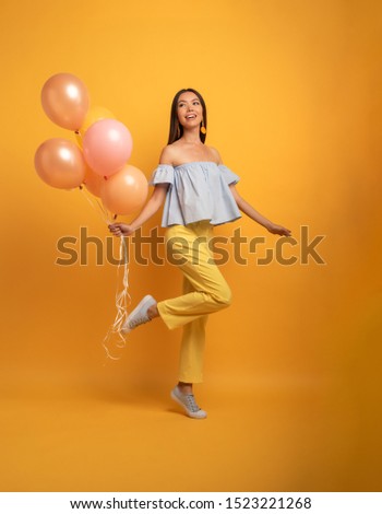 Girl ready for a party with balloon. Joyful an happiness expression. Yellow background
