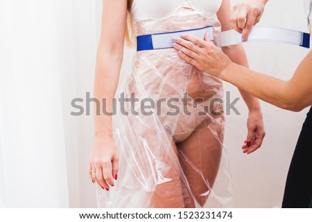 The process of anti-cellulite vacuum therapy with a bag. Preparation in progress. Picture with copy space. The doctor's hand helps put on the nylon