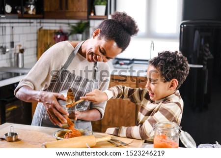 Son is helping mother to prepare pumpkin pie. American family. Single mother. Household chores for kids. Royalty-Free Stock Photo #1523246219