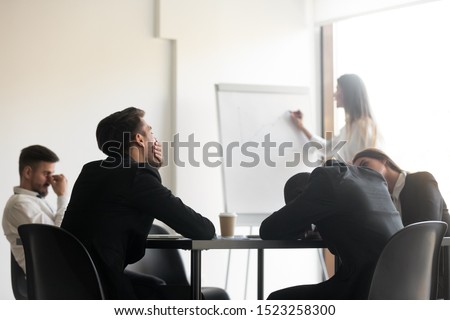 Bored unmotivated diverse team of employees feeling lack of interest during educational workshop. Sleepy manager feeling tired at lecture. Yawning businessman distracted from corporate training.