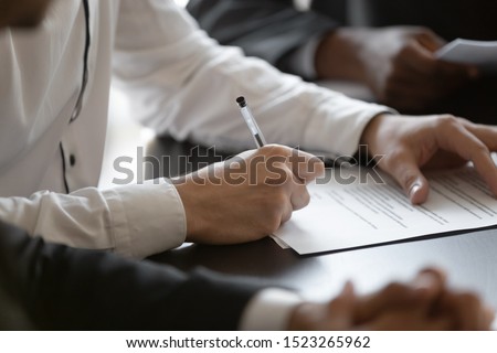 Close up young male employee manager customer hands signing paper contract after checking. Millennial investor client put signature at business agreement between partners. Editor making corrections. Royalty-Free Stock Photo #1523265962