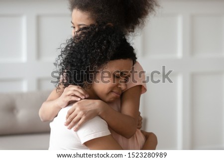 Close up upset loving affectionate african american young woman embracing little kid daughter, give support, helping with problems or bullying, comforting, expressing love, feeling sorry, apologizing Royalty-Free Stock Photo #1523280989