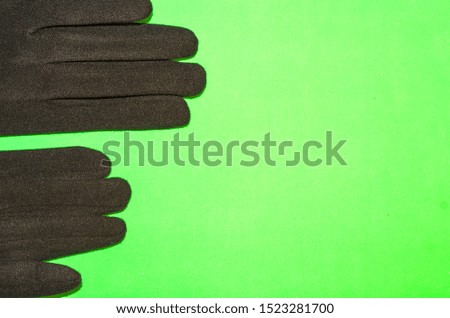 Black woolen gloves at green background