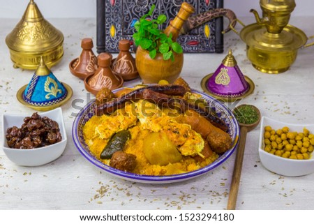 Couscous Royal meal with vegetable, sausages and meat in a traditional Morocco plate, served with Arabia decoration.