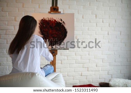 Beautiful girl artist at work in a creative white studio