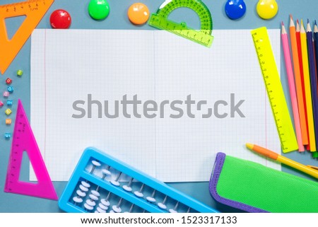 Blank school notebook with copy space and school accessories on blue flat lay background. Back to school concept.