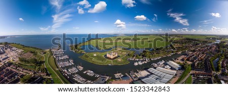 Wide aerial panoramic view of the Muiderslot castle in Muiden near Amsterdam and its lush gardens at the IJsselmeer with surrounding water entrenchment and port area and harbour of the historic city