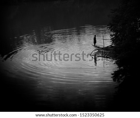 Man on a boat by the river in artistic black and white