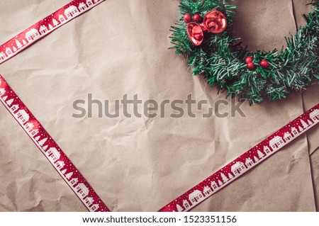 Rumpled kraft paper with red christmas ribbon and festive wreath. Template for a christmas card.