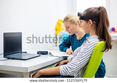 Young teenage girl and child therapist during EEG neurofeedback session. Electroencephalography concept.  Royalty-Free Stock Photo #1523369579