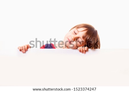 Cute sleepy little child girl behind white empty banner. Free space for text.