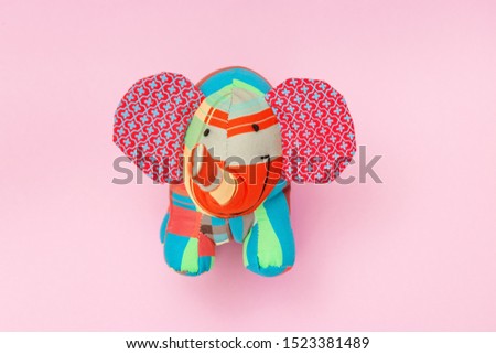 Bright children's toy colorful elephant on pink paper background with copy space. Childhood, happiness concept. 