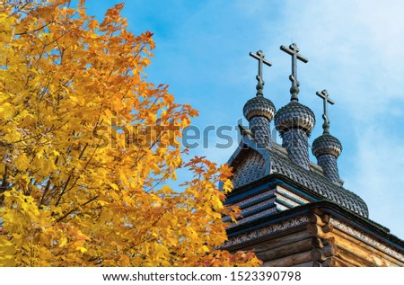 Old wooden church on a background of yellow maple leaves.