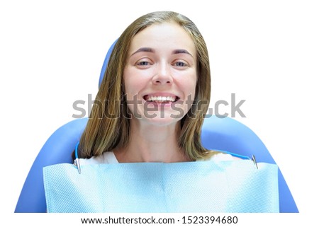 Girl sitting in a dentist's chair smiling while looking in the camera isolated on the white background.