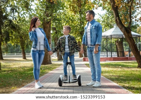 Modern family, dad mom son rides a hoverboard in the park, self-balancing scooter. Active lifestyle technology future.