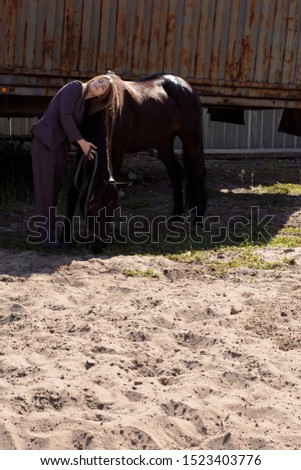 Pictures beautiful woman in a suit hugs a horse
