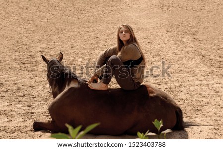 Pictures proud girl rider sitting on a horse in the sand