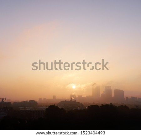 Early morning sunrise through polluted city air Canary Wharf financial district London