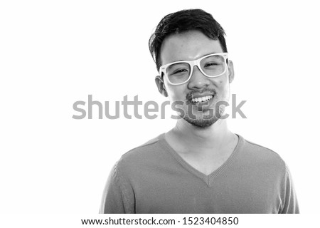 Studio shot of young happy Asian man smiling while wearing eyeglasses