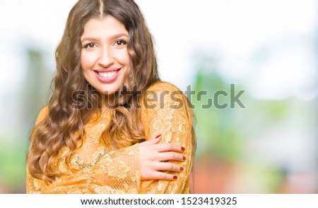 Young beautiful woman wearing yellow elegant dress happy face smiling with crossed arms looking at the camera. Positive person.