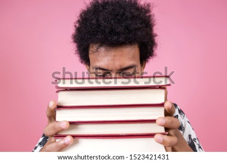 Portrait of a smart African man holding a stack of books close up