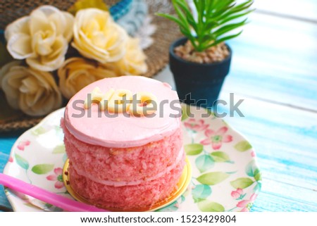 Mini pink cupcake with letter word HBD (Happy Birthday), Happy ceremony with sweet pastry decorative flowers, small plant on blue wooden plank, closeup selective focus 